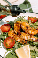 Pouring golden olive oil over seafood salad, combining grilled shrimp with crisp vegetables and greens.
