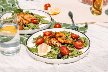 Grilled king prawns on a bed of fresh arugula, with juicy cherry tomatoes, black olives and lemon wedges. A perfect Mediterranean salad.