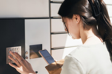 Young woman using smartphone by locker
