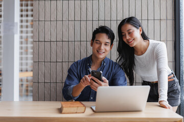 Young asian entrepreneurs collaborating on a project using smartphone and laptop