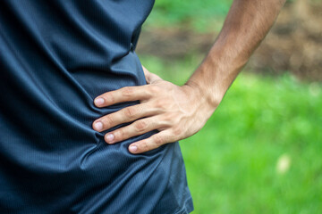 A young boy holds his waist with one hand for pain