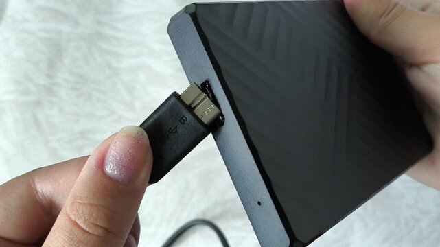 Female hands connect the cable to an external HDD hard drive. Additional memory card for PC, laptop.