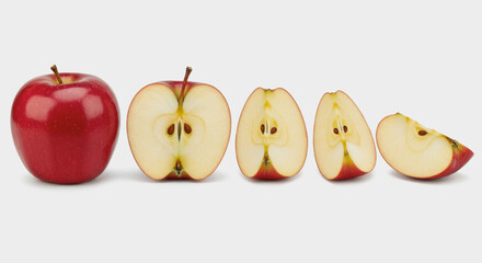 Red apple whole and sliced into pieces on a white background.