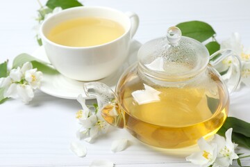 Brewed green tea with jasmine in cup and teapot on white background