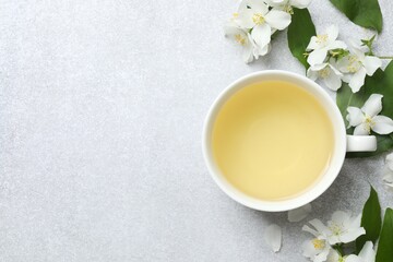 Cup of hot tea with jasmine flowers on gray background, close up