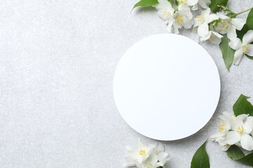 Beautiful white jasmine flowers with paper card on gray background. top view, space for text