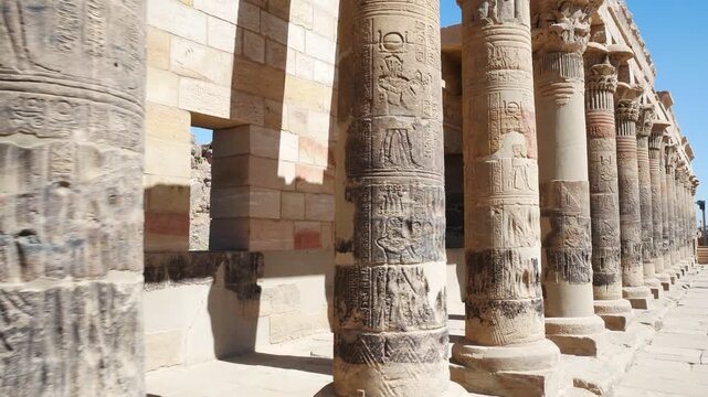 Row of ancient columns in a perspective view at the famous Philae temple, Aswan, Egypt. Blue sky on the background.