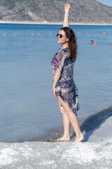 Woman Enjoying a Sunny Day at the Beach With Clear Blue Water and Scenic Mountains in the Background