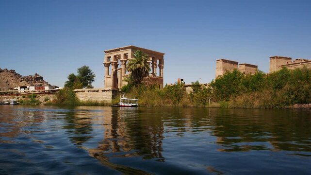 Philae island, viewed from the calm waters of river Nile, Aswan, Egypt. The famous temple on the background, with blue sky.