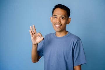 Portrait Of A Smiling Person Showing A Positive Gesture Against A Blue Background