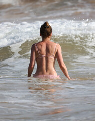 A woman is standing in the ocean wearing a pink bikini