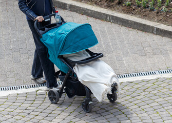 A woman is pushing a stroller with a blue canopy