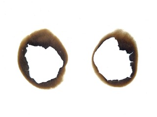Close up of fire burned hole on white paper background. Burnt paper. A piece of scorched and torn...