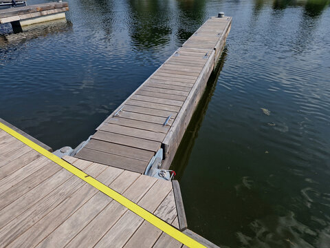 anchoring concrete footings hold the concrete floating pier by the metal rods. chains and ropes as insurance in case of flood. wooden paneling and coarse mesh as railings