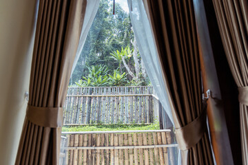 Window view with bamboo fence and green trees outside ryokan offering Japanese style rest and relax...