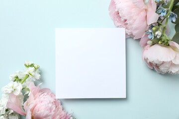 Top view photo with pink peonies and paper card on blue, top view, space for text