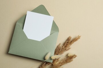 Green paper envelope with beautiful dry flowers on pastel background. Ideal for wedding invitations