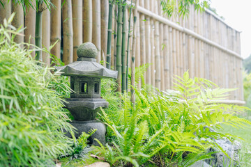 Japanese ryokan garden with stone lantern and bamboo fence creating peaceful style space to rest...