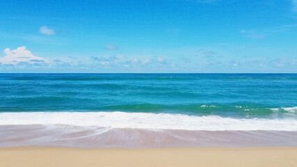 Obraz premium Serene Beach Panorama: A sweeping view of a pristine sandy shore, where azure waves gently lap against the golden sand, under a clear cerulean sky.