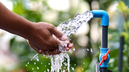Quenching Thirst, Fresh Water: A person cups hands under a stream of pure, fresh water from a blue...