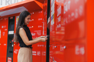 Young woman collecting parcel from automated locker post office