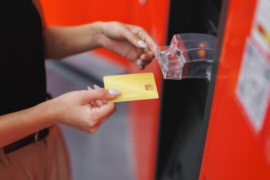 Woman paying with credit card at red atm machine - Powered by Adobe