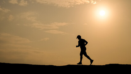Silhouette of runner under the sun: A silhouetted figure of a runner strides confidently against...