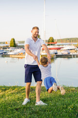 Smiling Father Playing With Child Near Marina Outdoors