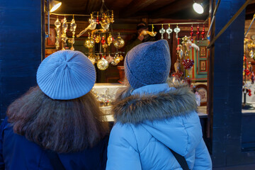 Women admiring Christmas ornaments at a market stall.