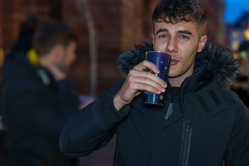 Man enjoying a warm drink at a winter market.