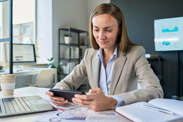 Businesswoman checking smartphone notification in modern office
