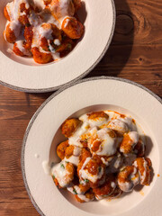 Two Bowls of Turkish Fellah Köftesi with Yogurt Sauce on a Wooden Table
