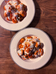 Two Plates of Traditional Turkish Bulgur Meatballs Served with Yogurt on a Wood Surface