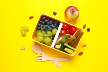 Packed lunch with sandwiches, fruits, nuts and vegetables in a divided container
