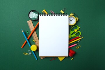Top view of school stationery and notebook on green background, top view