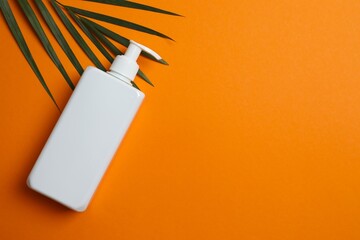 Closeup of white sunscreen bottle on orange surface, space for text