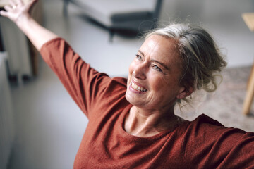 Smiling woman in a loft with arms raised showing a happy attitude