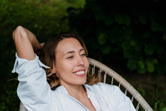 Woman smiling and relaxing outdoors in a garden, eco living concept
