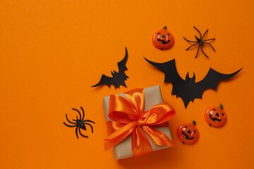 Halloween composition with gift box, pumpkins, candies, bats and spiders creating a spooky...
