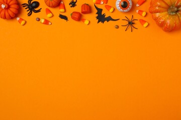 Festive Halloween decorations arranged on orange background 