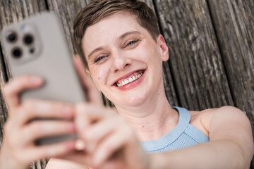 Happy woman smiling taking selfie on terrace in casual blue top