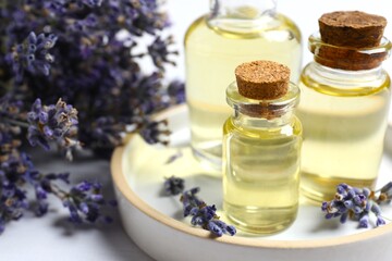 Bottles of essential oil for aromatherapy, alternative medicine or perfumery and a bouquet of fresh lavender on a light background. Banner, space for text.
