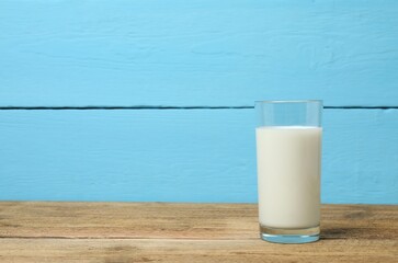 Big glass of milk with napkin on old wooden table. Dairy products
