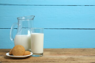 Jug and glass of milk with cookies on table