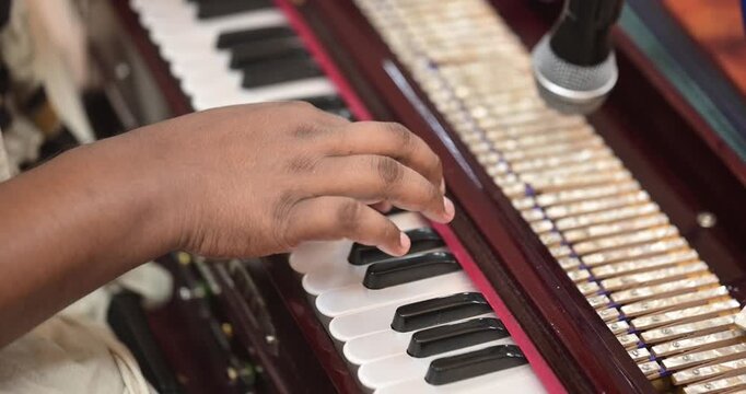 An Indian musician playing harmonium with graceful hand movements and focused posture, creating soulful traditional music