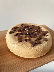 Homemade cake with chocolate on a wooden board against a white wall