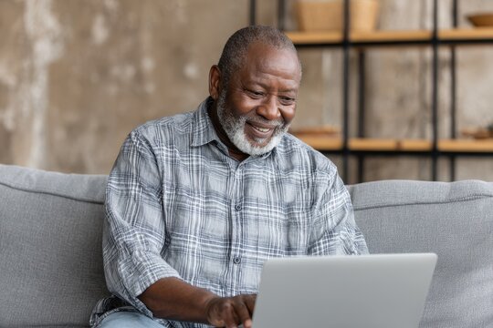 Senior African American Man on Sofa Using Laptop for Online Communication