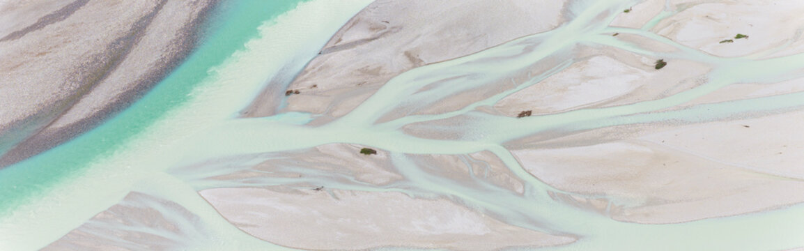 Iconic Italian river Tagliamento, Friuli, Carnia, Italy. Aerial view of the braided riverbed with turquoise water flowing through gravel banks and sparse vegetation.