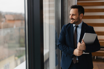 Fototapeta premium Portrait of handsome businessman with a laptop in company