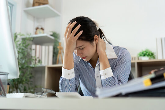 Office Syndrome: Woman holding her head in distress at work